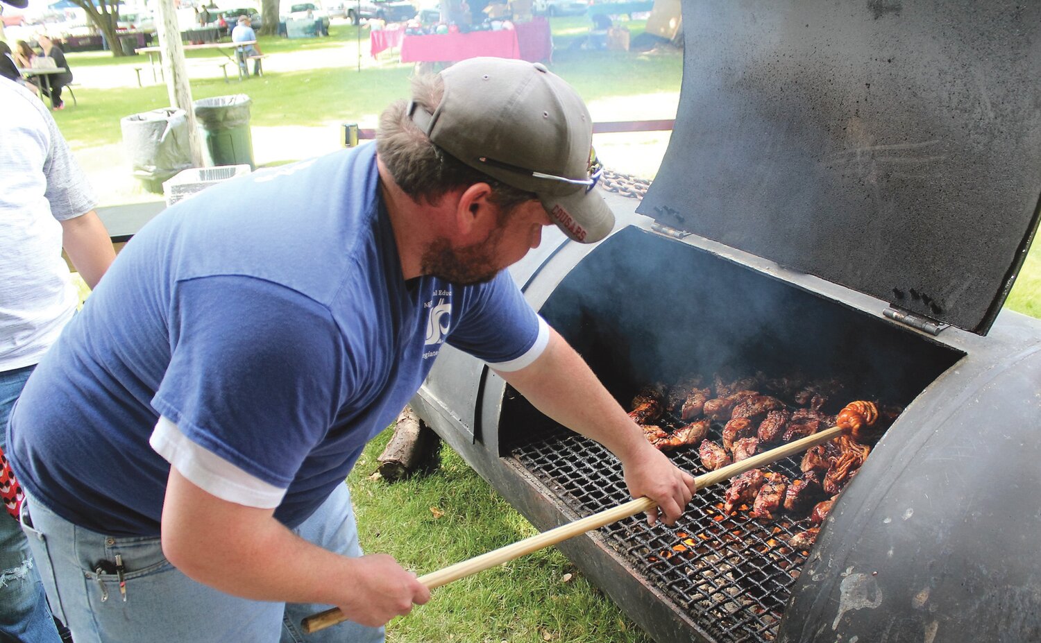Bridgeport FFA advisor, Adam Corum applies barbecue sauce to pork ribs at the FFA food concession in fireman Park.