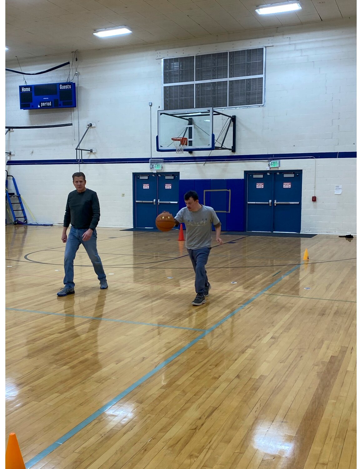 Chelan Special Olympics Assistant Coach Steve Hilde works with athlete and son Michael Hilde on basketball skills.