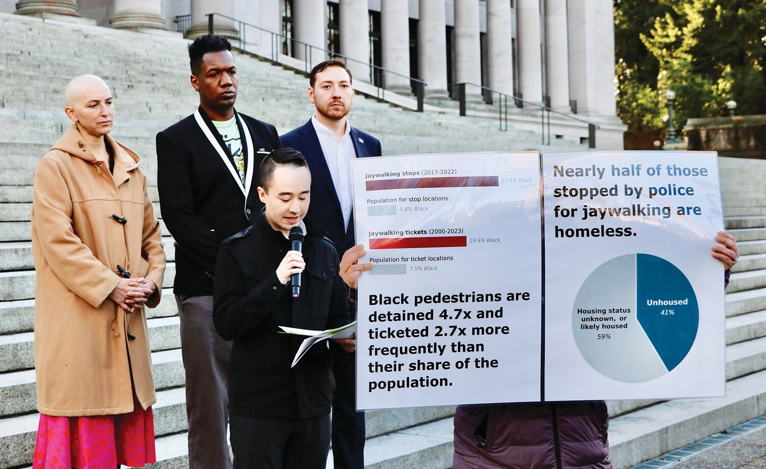 Taking their arguments on jaywalking to the steps of the Capitol in Olympia are, from left in the back row: Sen. Rebecca Saldana, community member DeAndre Anderson, Advocacy Director at Transportation Choices Matthew Sutherland, holding microphone, and research partner Ethan C. Campbell. Jan. 23. Transportation Choices held a press conference on the north steps of the Washington State Capitol to unveil a new research report that shows disparate impacts of jaywalking enforcement.