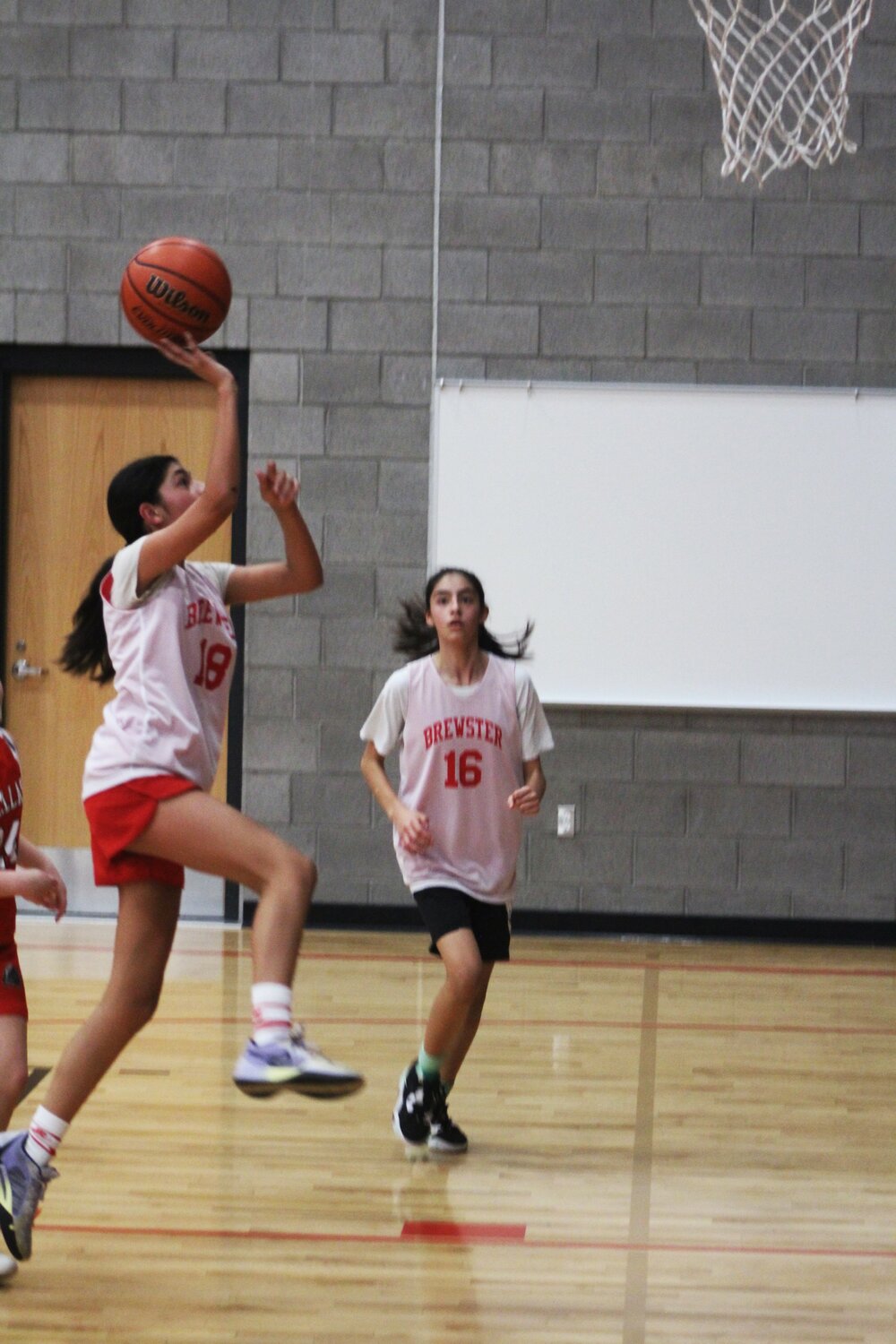 Kamillah Hurtado, left, drives to the basket as twin sister Isabella, 16, watches during the fifth-grade girls’ game between Brewster and Davenport during the three-day Path to the Podium tournament last weekend.