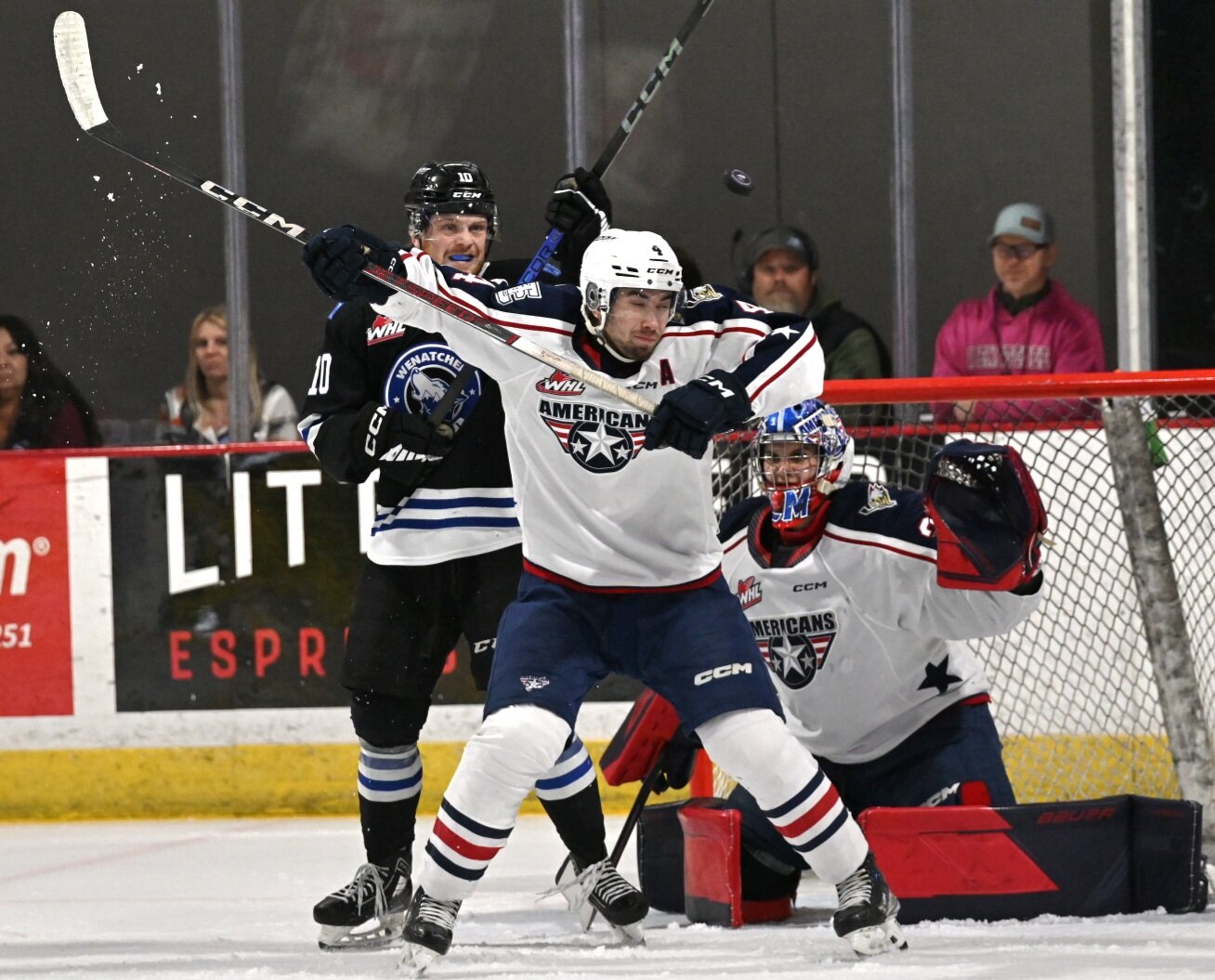 Wenatchee Wild forward Evan Friesen jostles with Tri-City Americans defenseman Ethan Peters (4, center) in front of Lukas Matecha (right) and the Tri-City net. Friesen scored the lone Wild goal Wednesday in a 4-1 loss to the Americans at Town Toyota Center.