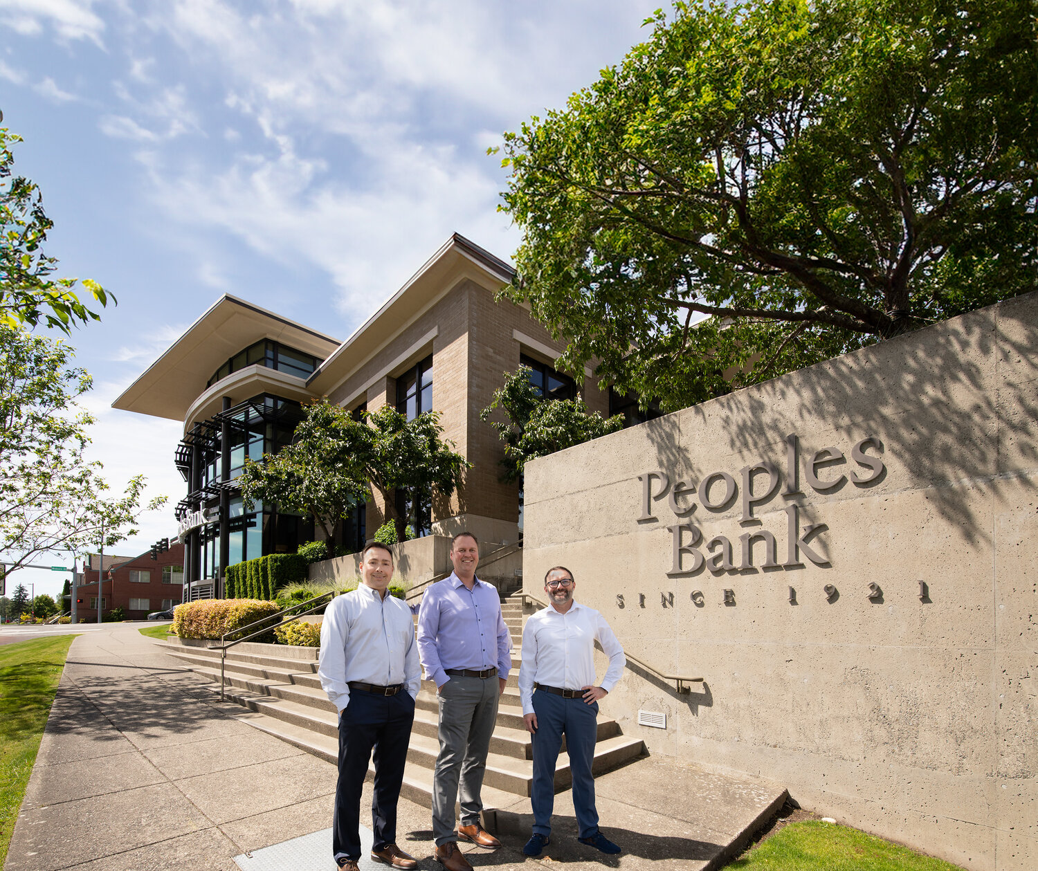 Newly appointed Regional Commercial Directors (from left) Jon Ensch, Mike Fredlund, and Alex Sansoni stand in front of Peoples Bank headquarters in Bellingham, Washington. The bank, established in 1921, announced their promotions as part of a strategy to strengthen commercial banking services across the state.