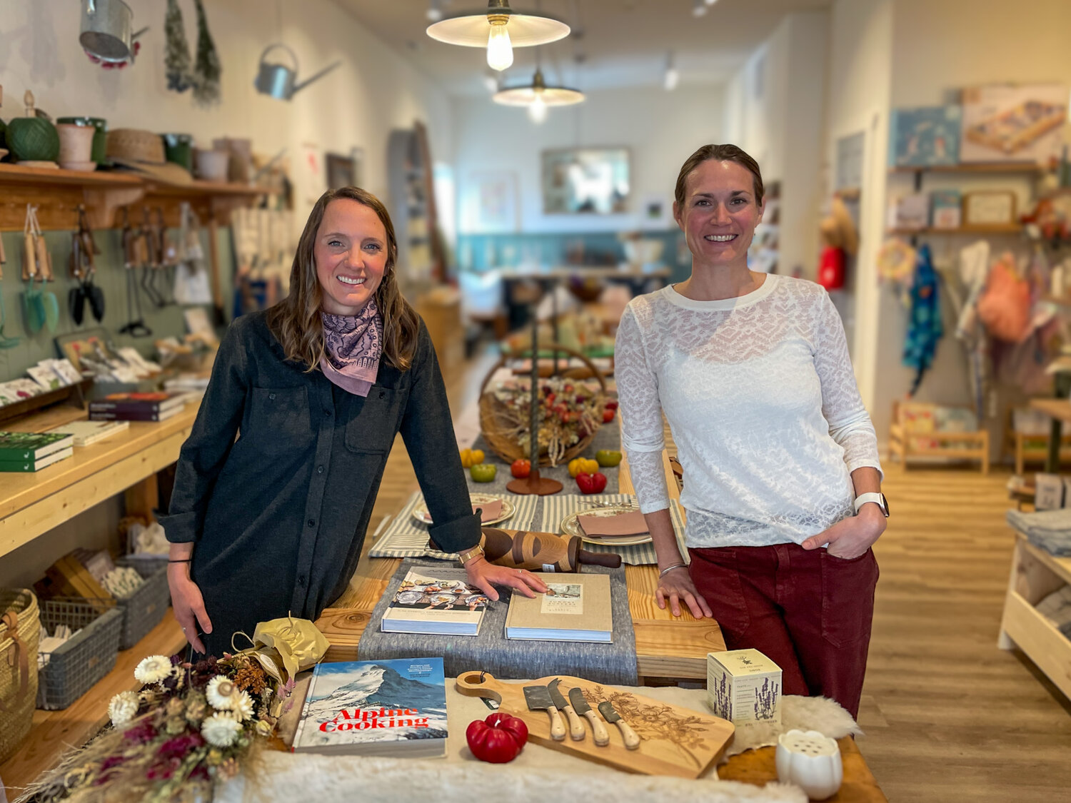 Owners Bri Davey and Hannah Dewey stand beside the boutique’s long tables, which are intended to create a gathering space for connection and creativity.