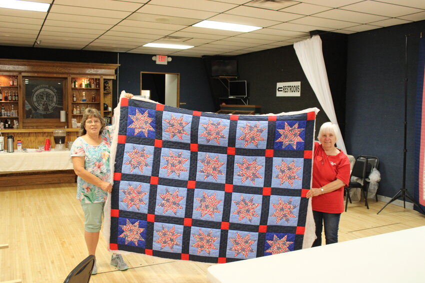 Virginia Hakenwerth and Charlotte Fry display a just-completed quilt during their meeting July 12 at the Elks Lodge in Warrenton. The quilt will eventually be donated to a Missouri veteran.