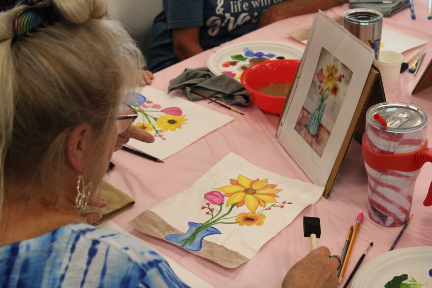 Sherry Smart works on her painting while checking out the original design made by instructor Carol Peper.