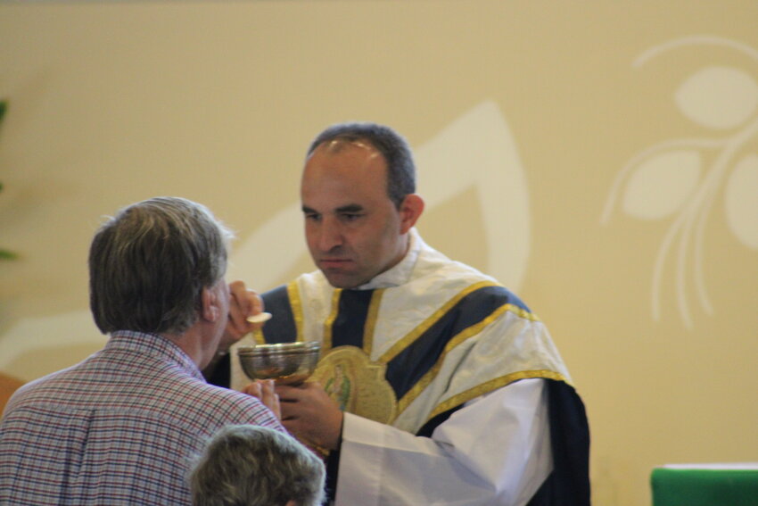 Father Eddie serves a parishioner communion during the 8 a.m. Mass on Aug. 22 at Holy Rosary.