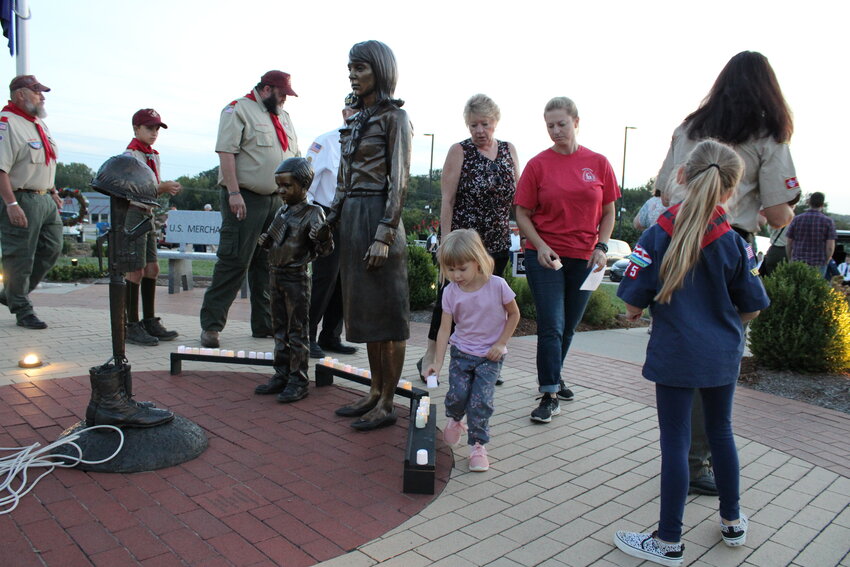 A young girl places here candle near the statues at the Tribute to Veterans Memorial in honor of America's POW/MIAs.
