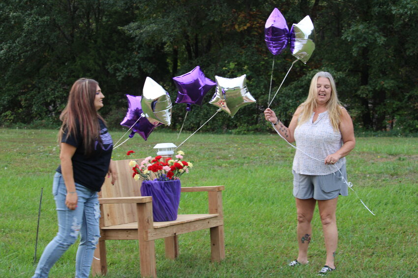 Alicia Davis and Sabrina Wipfler decorate the area near the billboards just west of Warrenton using purple and silver balloons and different colored flowers.