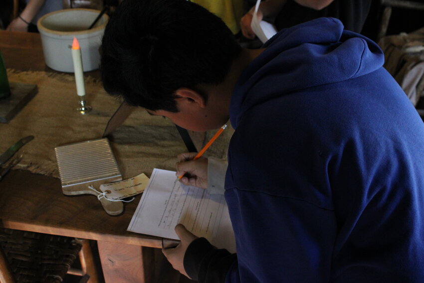 A Wright City Middle School student writes down the answer to one of the scavenger hunt questions given to the students before their visit to the Innsbrook historic village.