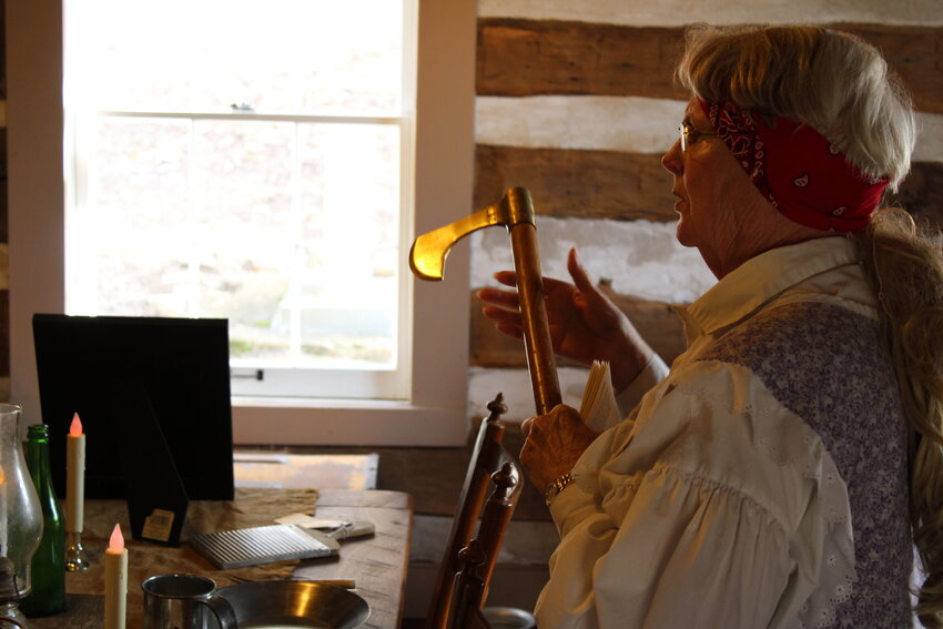Linde Flanders holds an ax as part of her presentation to Wright City Middle School students in the log cabin at the historic village in Innsbrook.