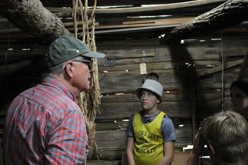 A Wright City Middle School student listens as Gary Barton presents inside the smokehouse at the Innsbrook historic village.