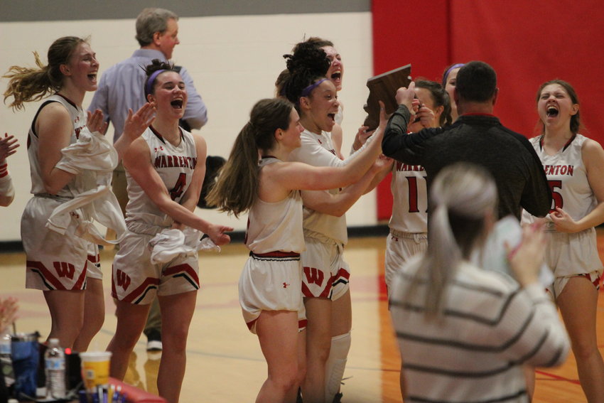 The Warrenton girls basketball team celebrates as Warrenton Acitivities Director Kevin Fowler gives them the district championship plaque. The Lady Warriors won the district final over St. Dominic High School 45-41.