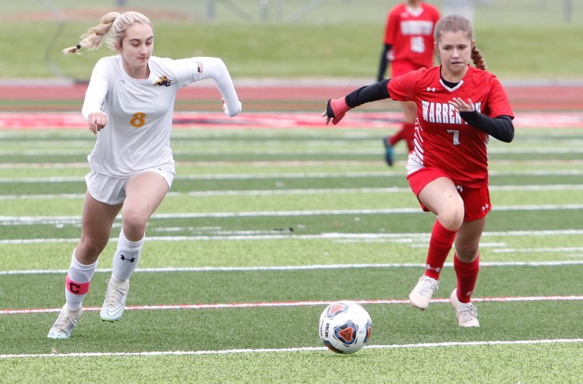 Alex Sutter (left) attempts to move the ball towards the goal as Ashlynn Reeves trails the play.