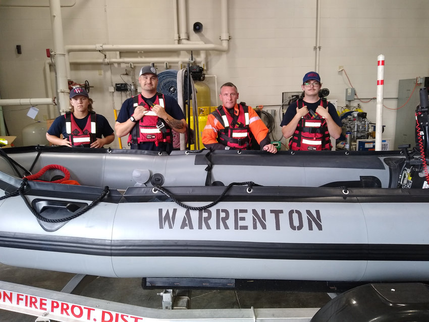 PREPARED FOR RESCUE &mdash; Warrenton firefighters demonstrate the life vests, suit and rigid inflatable boat that are involved in swiftwater rescues. Pictured, from left, are junior firefighter Ashton Dabbs, firefighter Justin Mosher, Capt. Matt Dabbs, and firefighter Nolan Patterson. Capt. Dabbs and Mosher were on the boat during last week&rsquo;s rescue, along with Chief Arron Lee of Winfield-Foley Fire District.