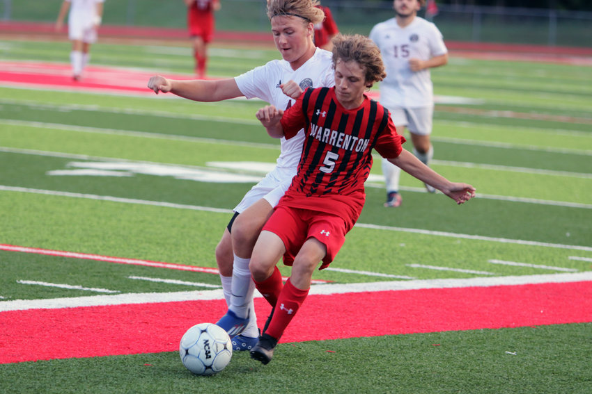 Warrenton midfielder Nolan Donovan (right) battles for possession of the ball with St. Charles West junior Ryan Beer.
