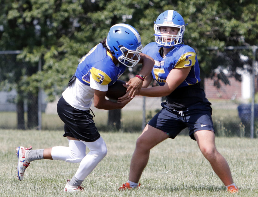 Wright City quarterback Joey Gendron (right) hands off the ball during the fourth day of Wright City&rsquo;s high school football camp last week.