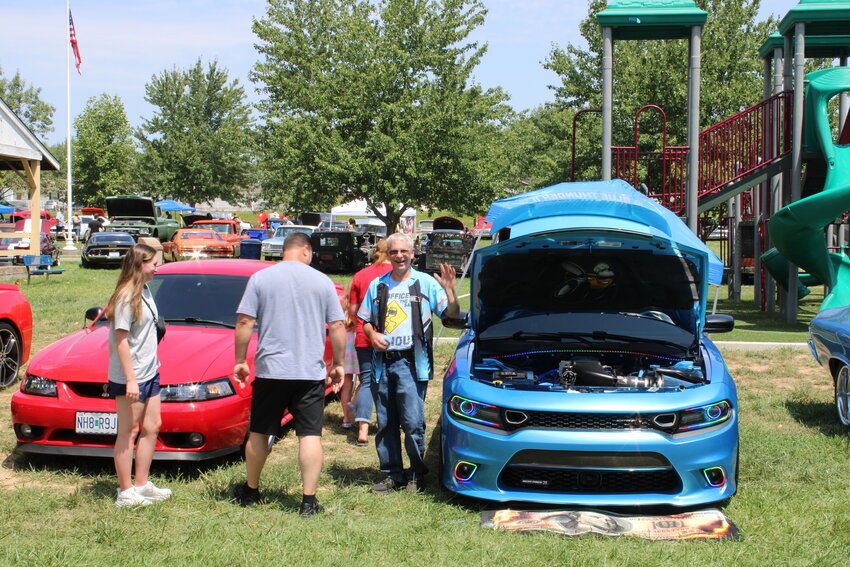 Keith Fisher, standing next to his 2019 Dodge Charger Scat Pack, waves during the Fat Heads Car Show on July 29 in Wright City.