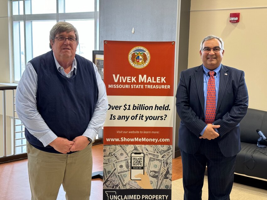 Warren County Treasurer Jeff Hoelscher and Missouri Treasurer Vivek Malek pose for a photo next to the banner that will be displayed at the Warren County Administration Building encouraging residents to check to see if they have money waiting for them.