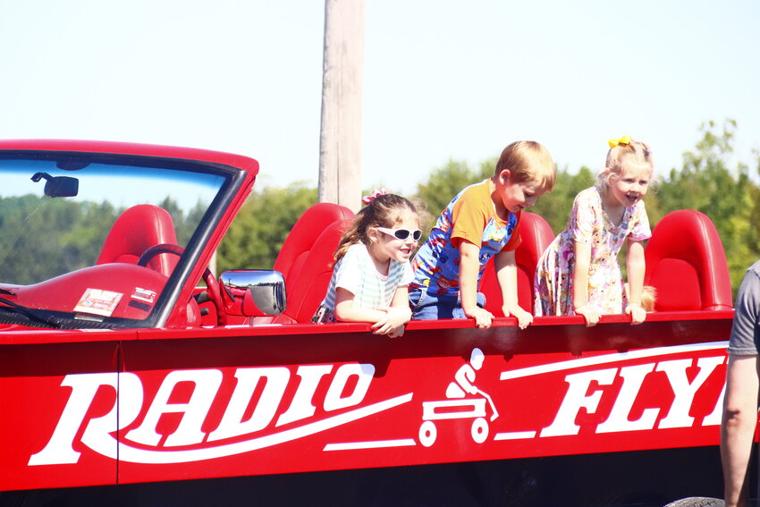 Jade Clark, 6, left, Jason Mizgate, 3, middle, and Willow Clark, 5, right, pose for a photo in the Radio Flyer Wagon at the Big Rigs event at Wright City Middle School.