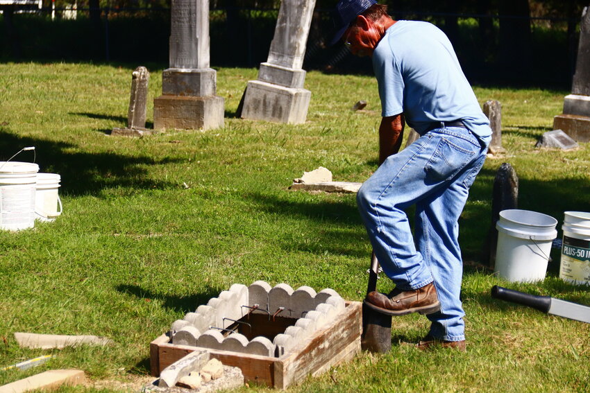 Gerry Prouhet works on refurbishing one of the headstones that had fallen in the cemetery. To fix the ones that have fallen, Prouhet creates a sort of cradle to hold the fallen headstone that is then placed next to the grave.