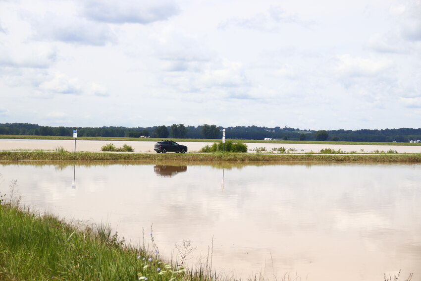 A car travels along Highway 94 just south of Treloar. Alongside the highway are two entire fields that still sat under two feet of water the day after the storm.