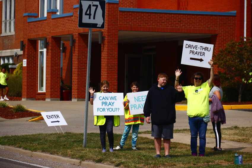 Volunteers cheered and waved signs at drivers passing on E Main Street in Warrenton, beckoning them to stop by the parking lot for Drive-Thru Prayer with Pastor Doug Kraus.