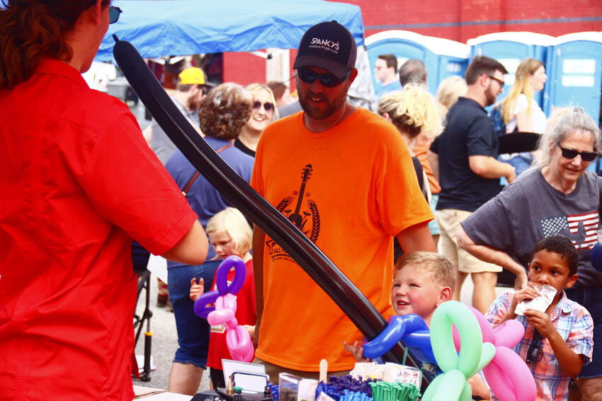 John Rekart and his son, CJ, 4, visit the Kids’ Korner at the Warrenton Fall Festival where CJ received his balloon sword.