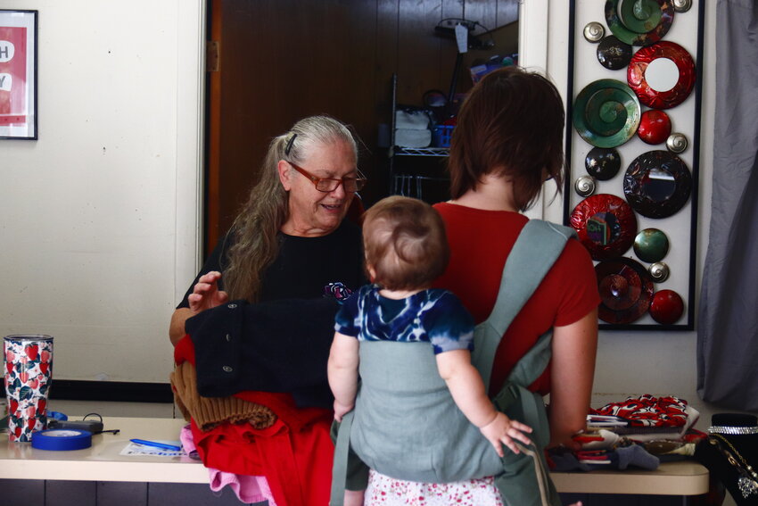 Volunteer Donna Engel helps Lilly Burton check out with Silas Willis in tow. She completed her shopping on the morning of the thrift store’s reopening on Oct. 1.