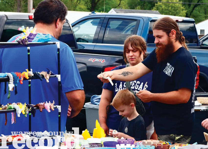 Maddie Carmi, middle, and Alex Carmi, right, purchase a miniature sheep from the game Minecraft for their son Kaiden at Wright City's First Fridays on Second Street on May 2.