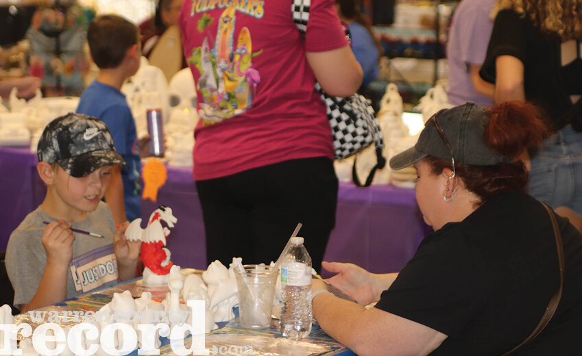 Dara Washburn and her son, Parker, work on painting ceramic figurines in the MaryLou Center during the day's festivities.