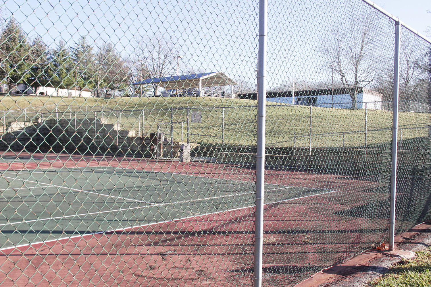 NEEDS TLC — Surface deterioration due to water seepage is visible at the tennis court in Warrenton's Morgan Park. Behind, on the right, is the facility for the city's decommissioned outdoor pool. City leaders want public input on what improvements to make at the park.