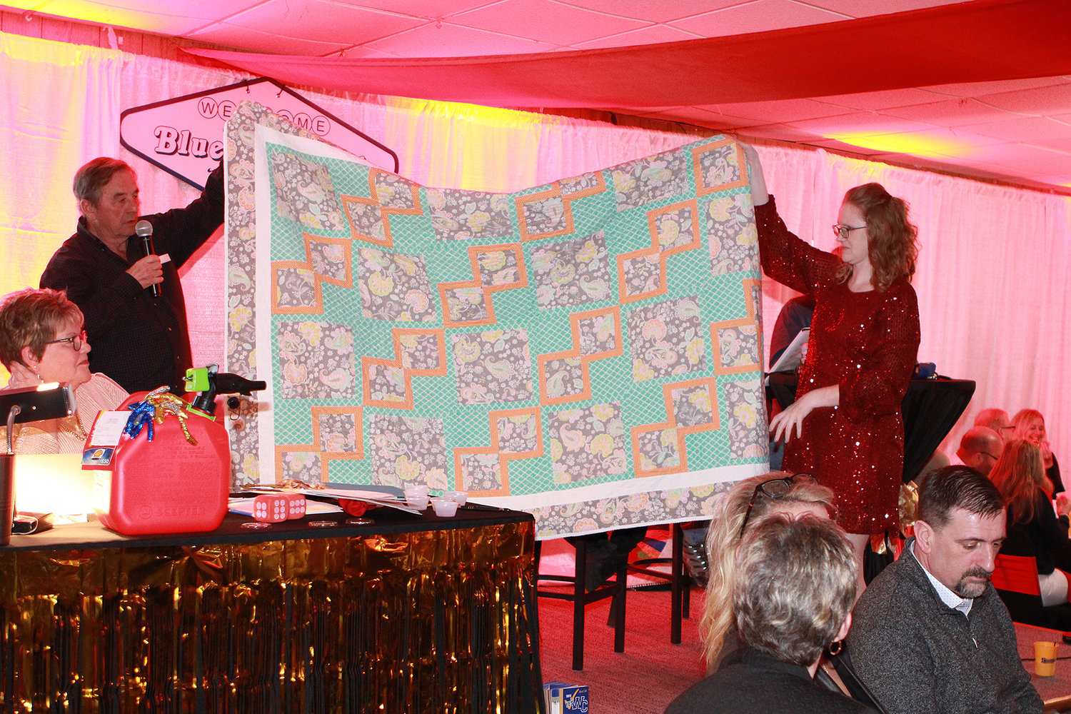 QUILT FOR AUCTION — Auctioneer Charlie Clark and volunteer Becky Schriener display a quilt that was one of dozens of items up for auction during the Blue and Gold scholarship fundraiser March 19.