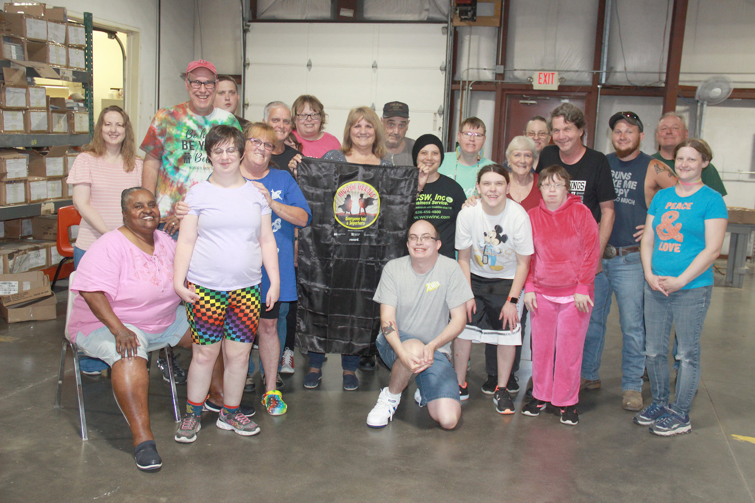 HIDDEN HERO — Warren County Sheltered Workshop Executive Director Jami Washburn displays her superhero cape alongside employees at the facility. Washburn was recognized for her work at the not-for-profit organization that provides employment for people with disabilities, as well as in the community.