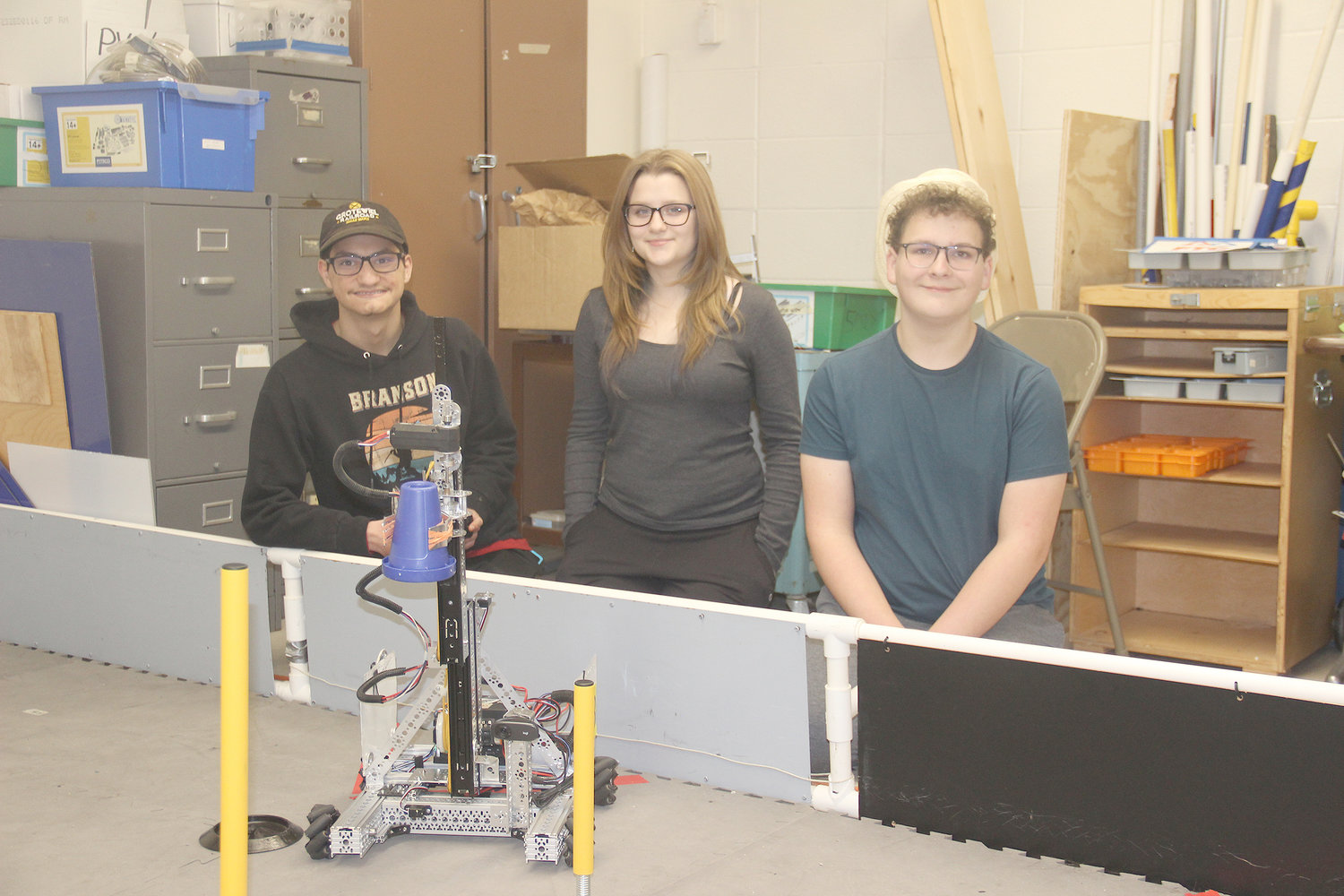 ROBOTICS TEAM — Sophomores Chase Grotewiel, Carlee Grueneberg and Luke Gens display their custom-built robot in a practice area at Wright City High School. Not pictured: sophomores Bee Padgett and Theory Ames.
