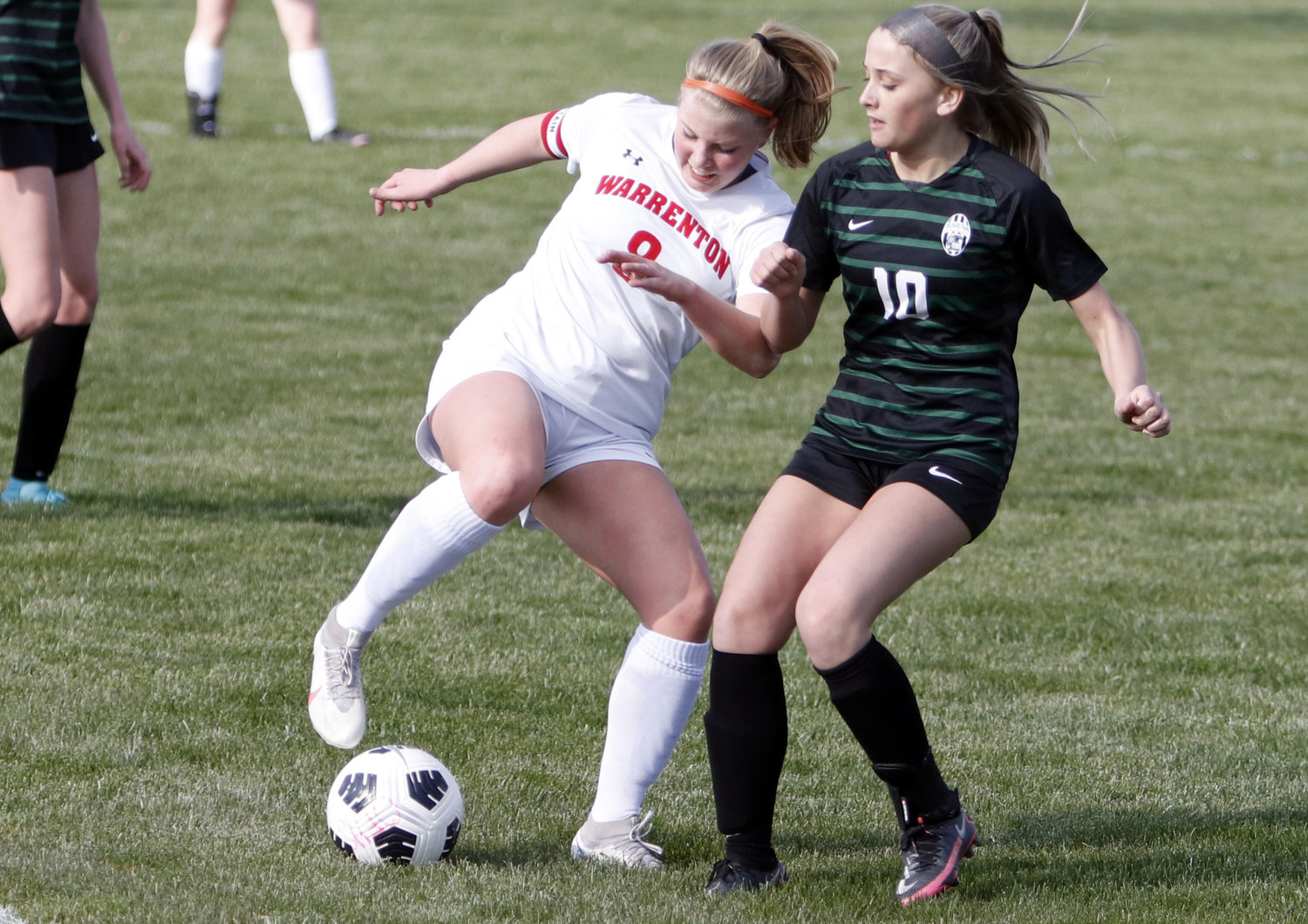 Warrenton midfielder Camryn Petersmeyer (left) looks to get past the Orchard Farm defense during the first half of Tuesday night’s loss.