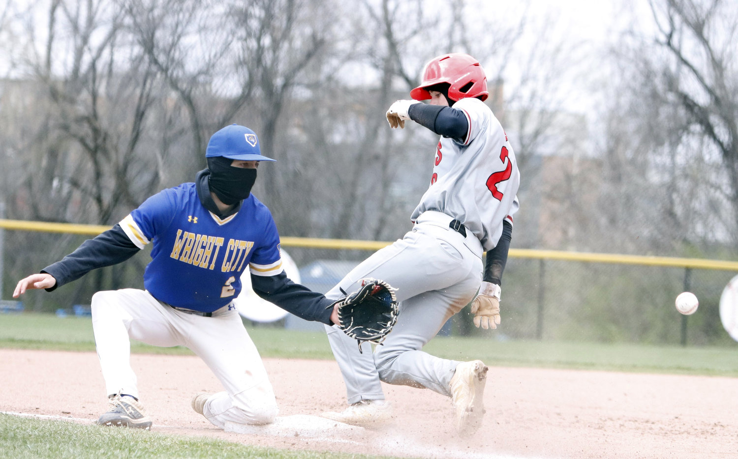 Wright City third baseman Nick Moore (left) prepares to catch a throw as Warrenton's Caleb Clark (right) slides into third base.