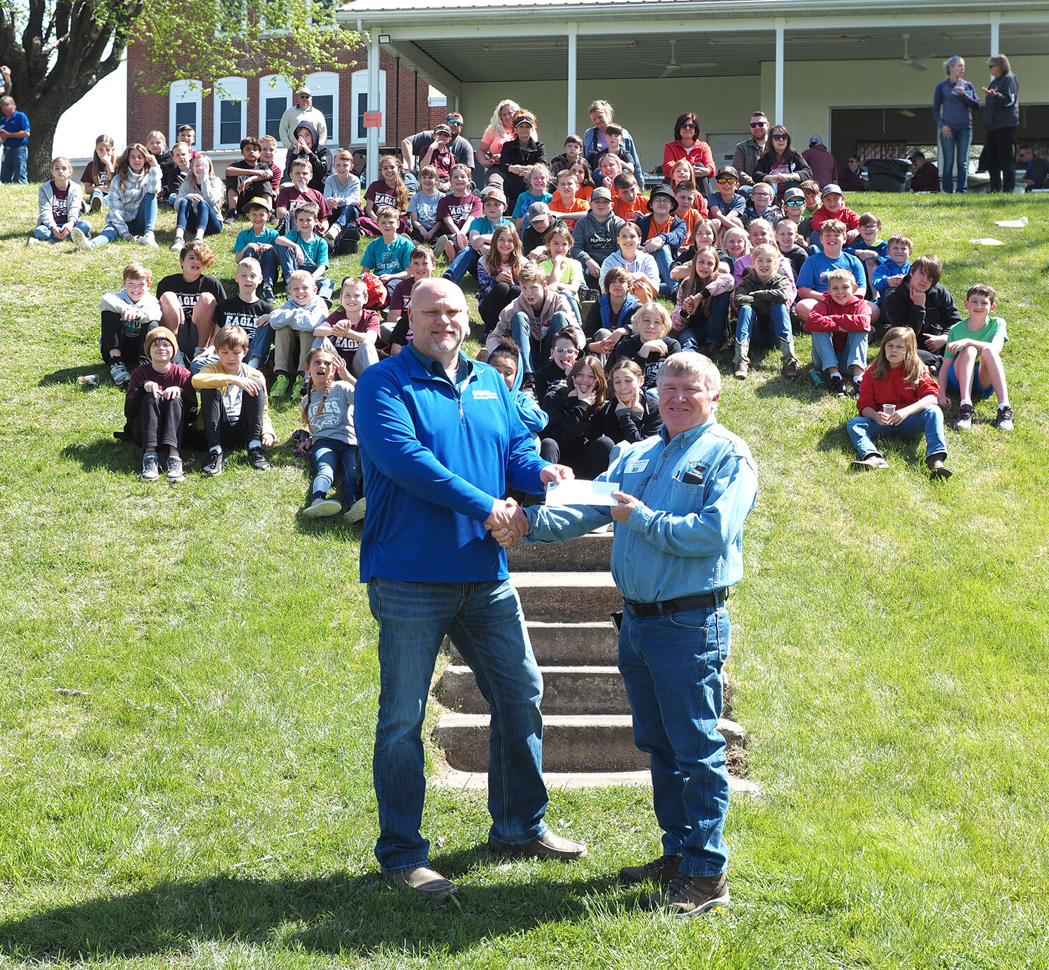 LUNCH DONATION — Gabe Twellman, member services of Cuivre River Electric Coopertive, presented Soil & Water Conservation District board member Charlie Schroer, a check for $1,000 to help cover the expense of lunch for the students. A meal was prepared by the Pork Producers. The tour returned to the Concord Hill area at St. Ignatius Catholic School on Tuesday, April 18. Students who attended the tour were from St. Ignatius, St. Vincent’s and Liberty Christian Academy.