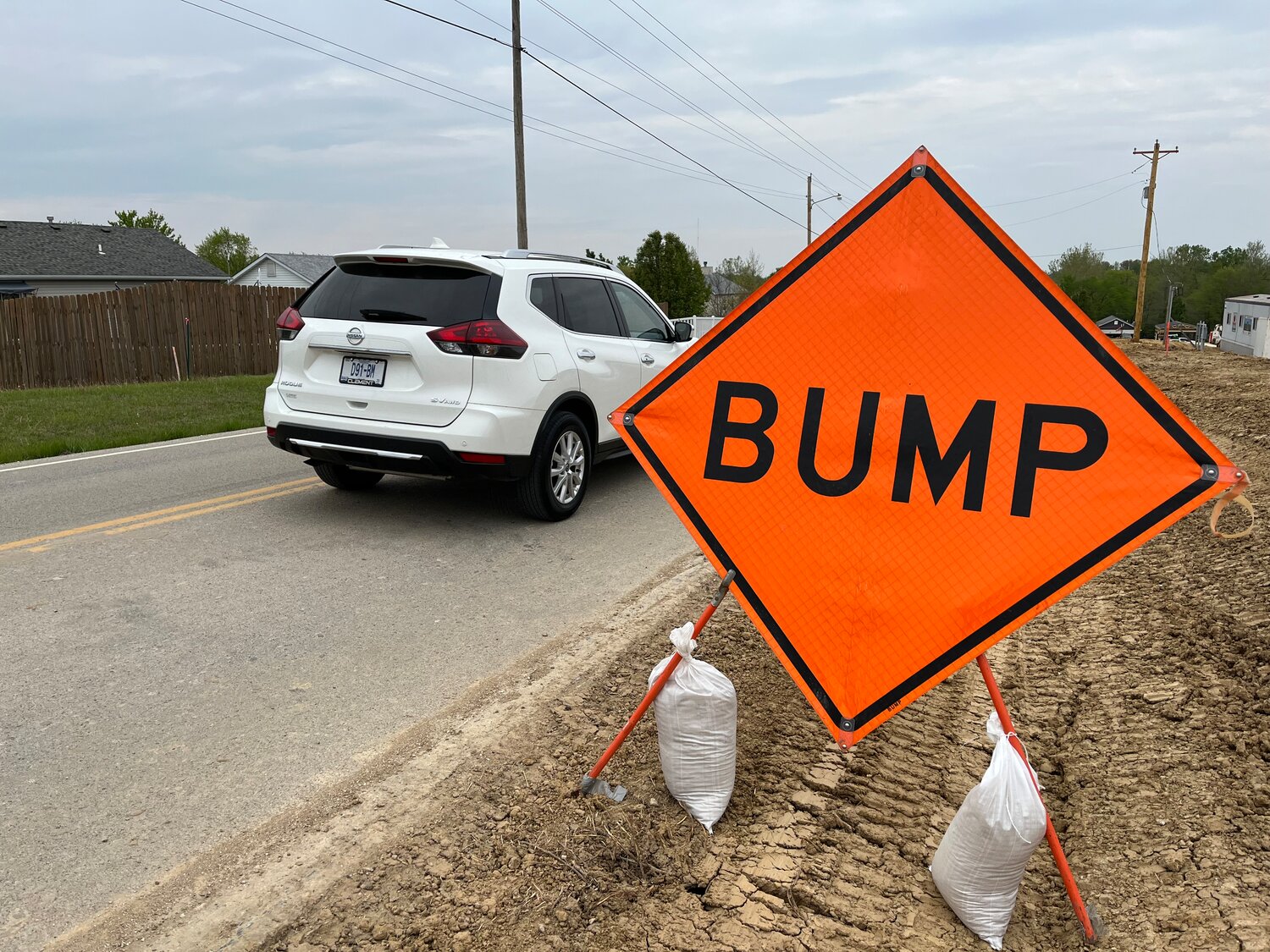 BUMP SIGNS - Large orange “bump” signs placed on both sides of Roelker Road warn drivers about the steel plates covering damage caused by trucks turning into the construction site of the new Wright City high school.