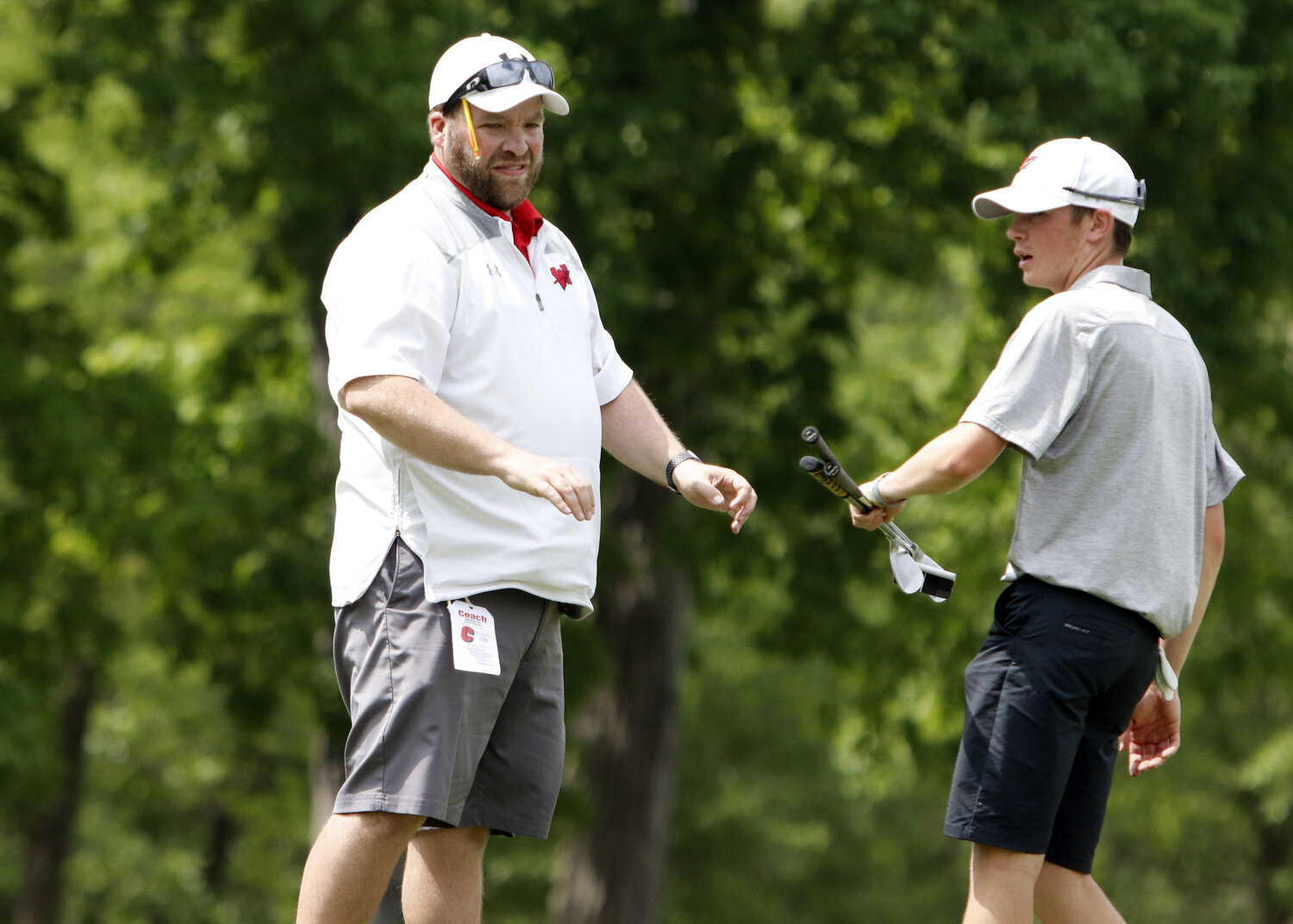 Warrenton head golf coach Aaron Jinkerson (left) hands a club to Owen Thompson after Thompson completed his round at the Golf Club of Wentzville.