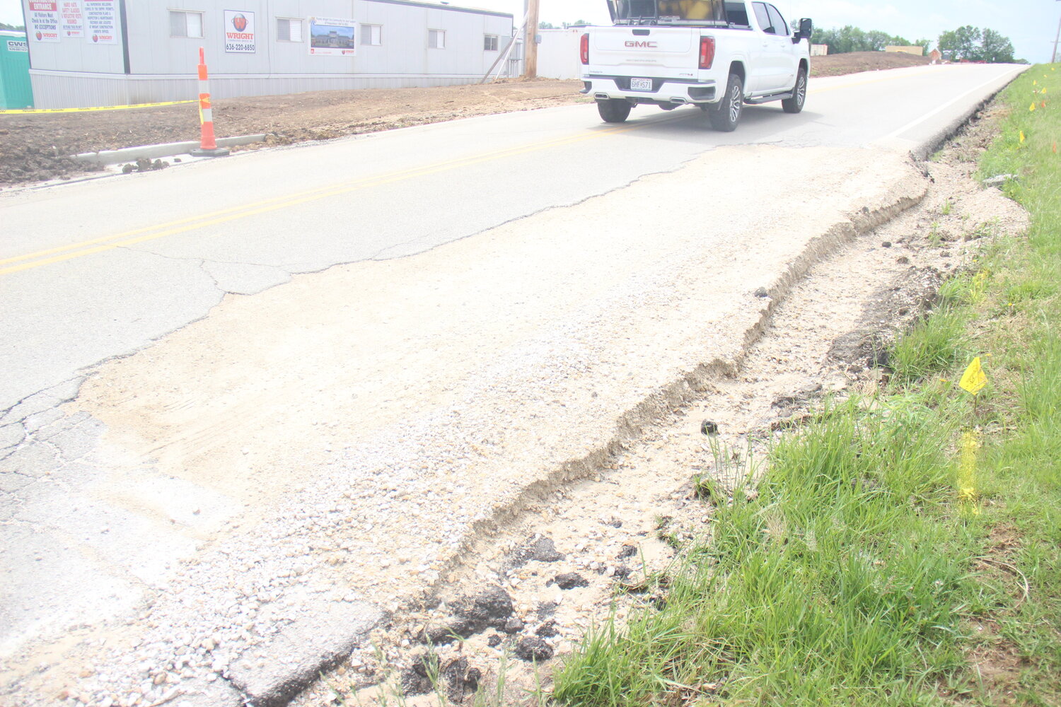 A truck drives past part of a deteriorating section of Roelker Road that has been filled with gravel.
