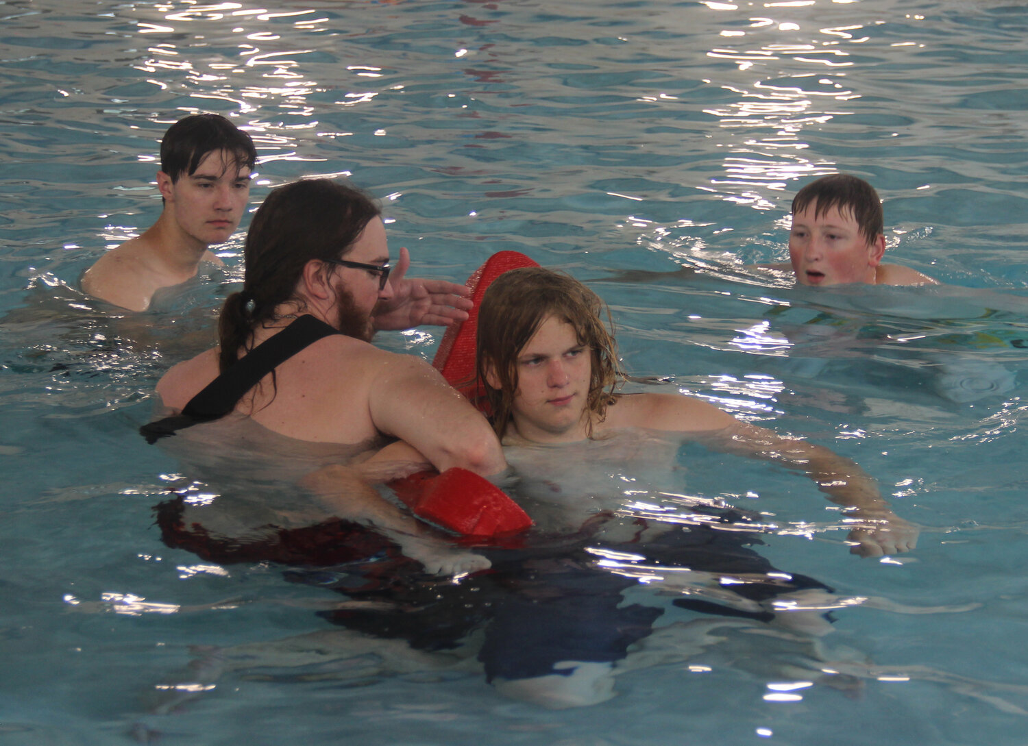 Cole McBride demonstrates the technique for a water rescue on Hudson Grube while Jacob Nagel and Cooper Stone watch.