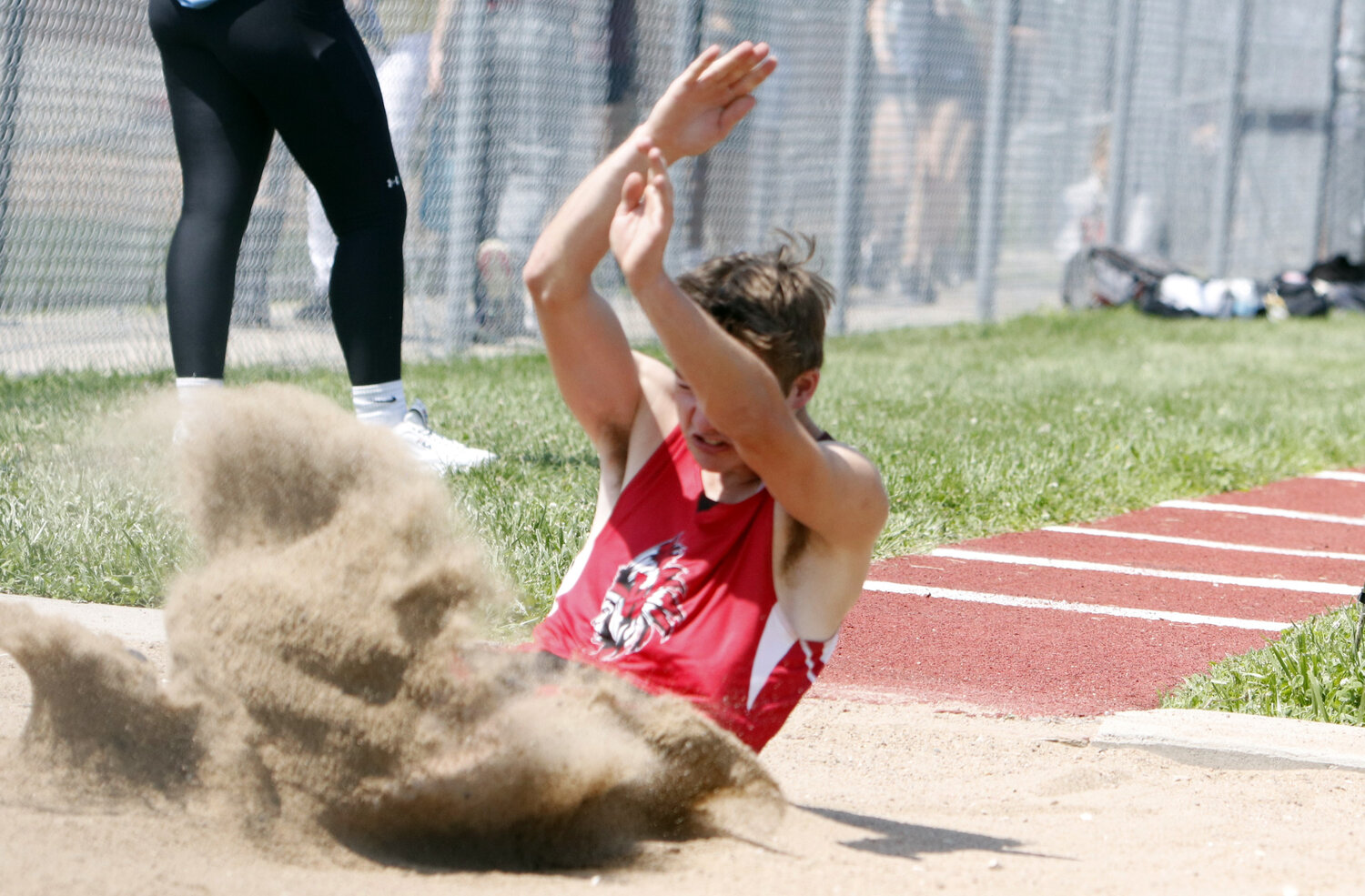 Colton Brosenne lands in the sand pit during the long jump competition.