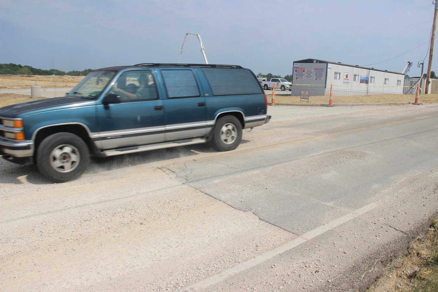 A vehicle drives over the newly-installed gravel where steel plates had once covered significant damage to Roelker Road near the entrance to the new high school construction site.