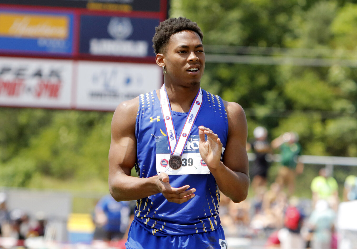 Wright City senior Jeremiah Davis claps while on the podium after receiving his medal for placing third in the 100-meter dash. Davis earned four medals at the state track and field meet last week.