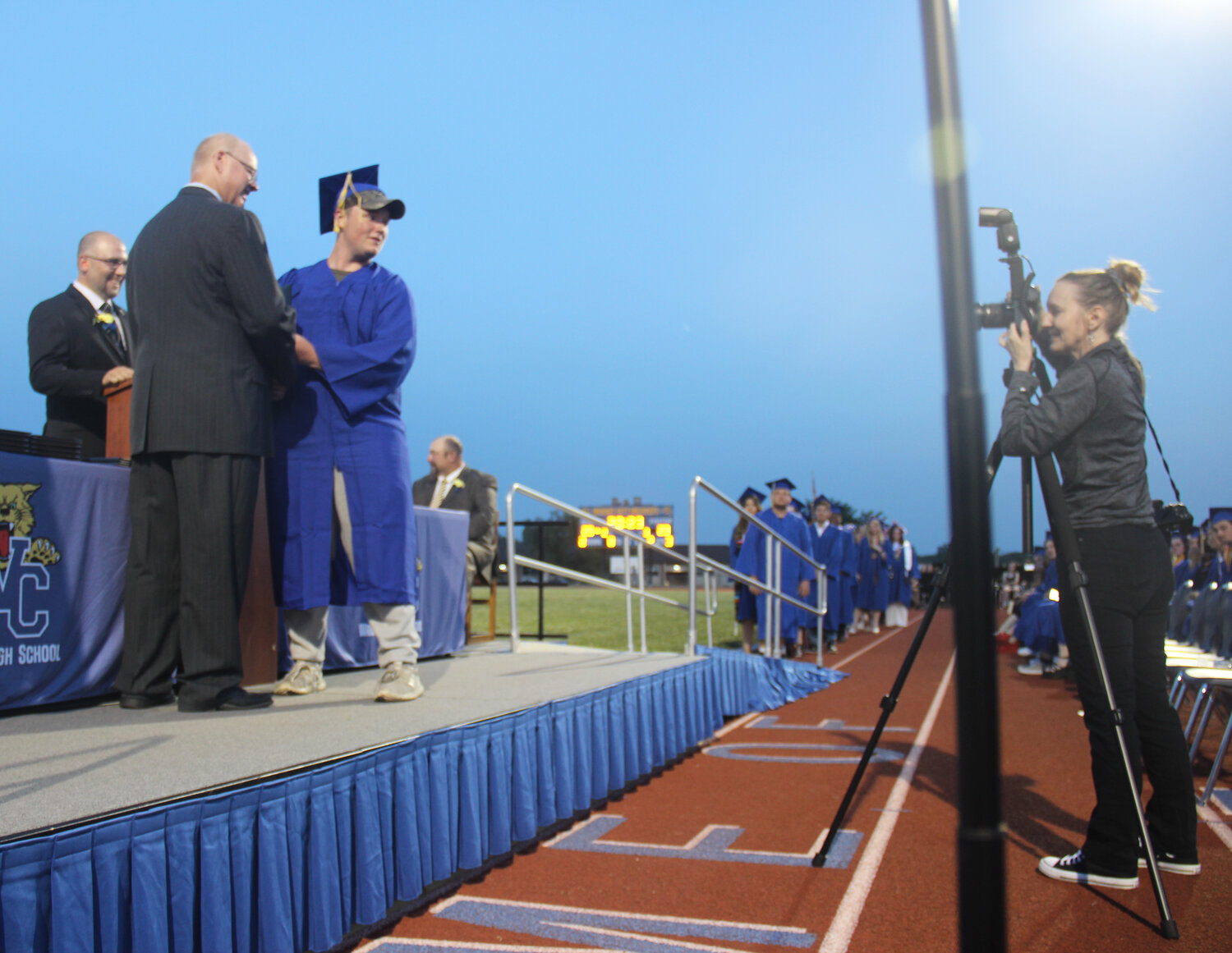 A Wright City High School senior poses with R-II School Board President Austin Jones while a photographer takes their picture during the graduation ceremony.