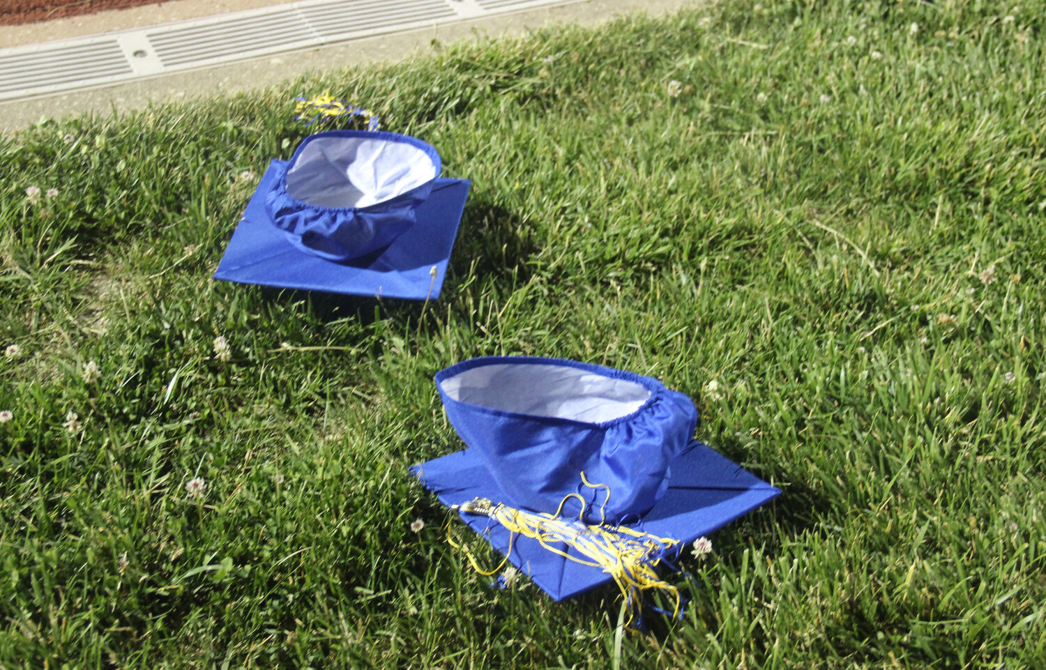 Two of the many caps that went airborne during the graduation ceremony landed on the football field waiting for their owners to retrieve them at the end of the graduation ceremony.