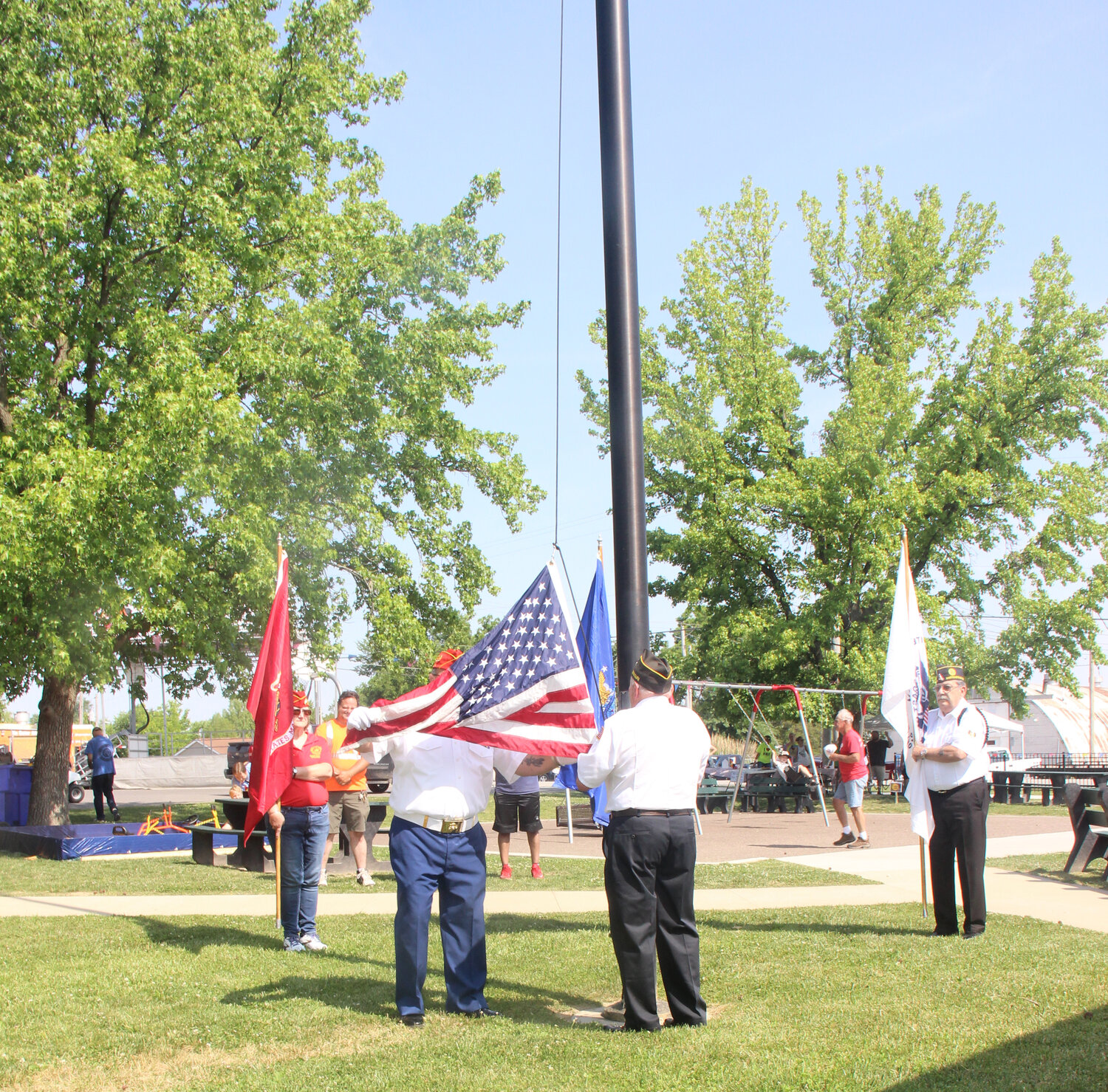 Rick Mantione, right, hoists the U.S. flag while Mike Buquet, the commandant to the honor guard, salutes.