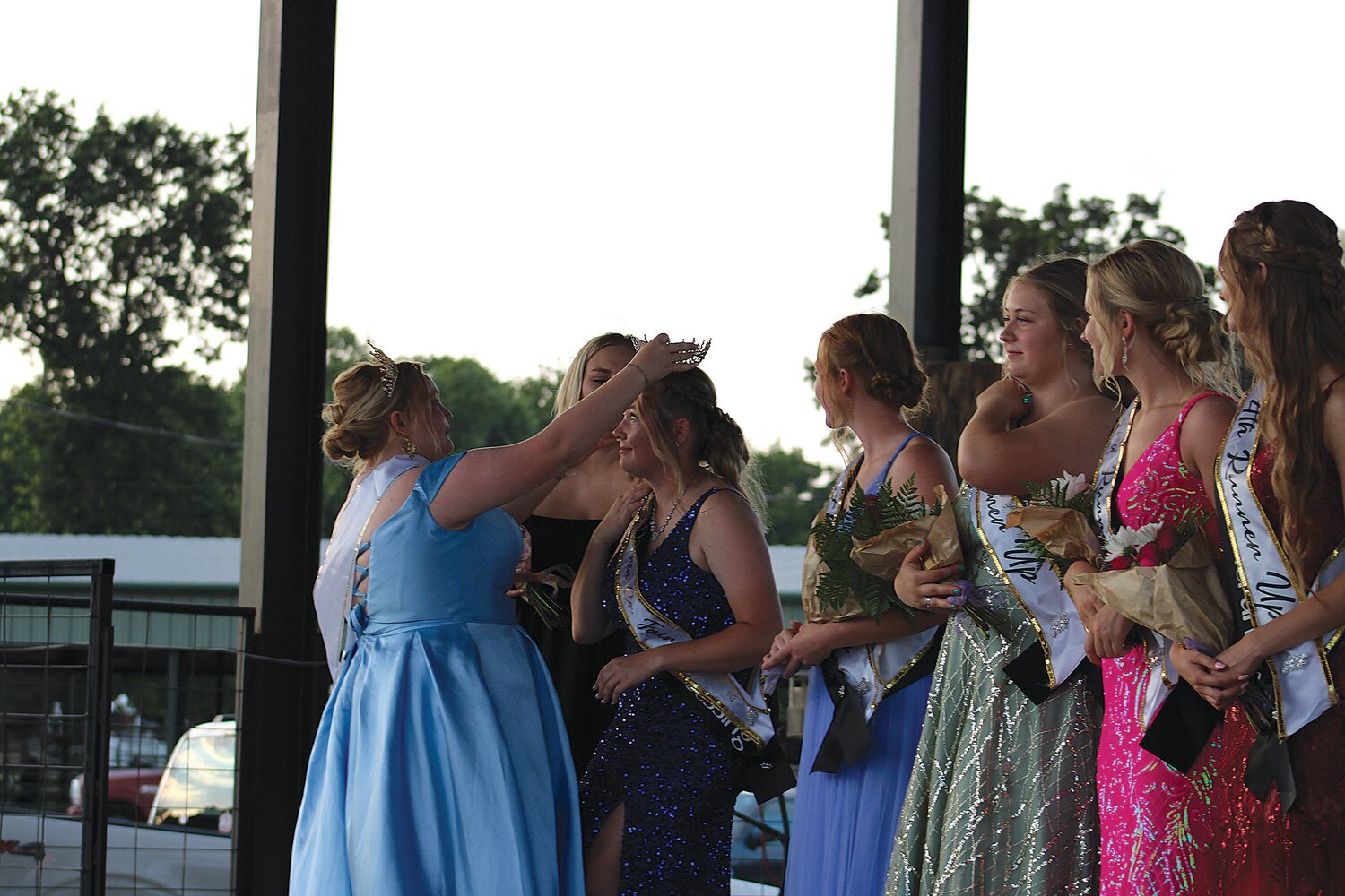 2022 Fair Queen Payton Duncan crowns 2023 Queen Kelsey Miller while the rest of the court looks on.