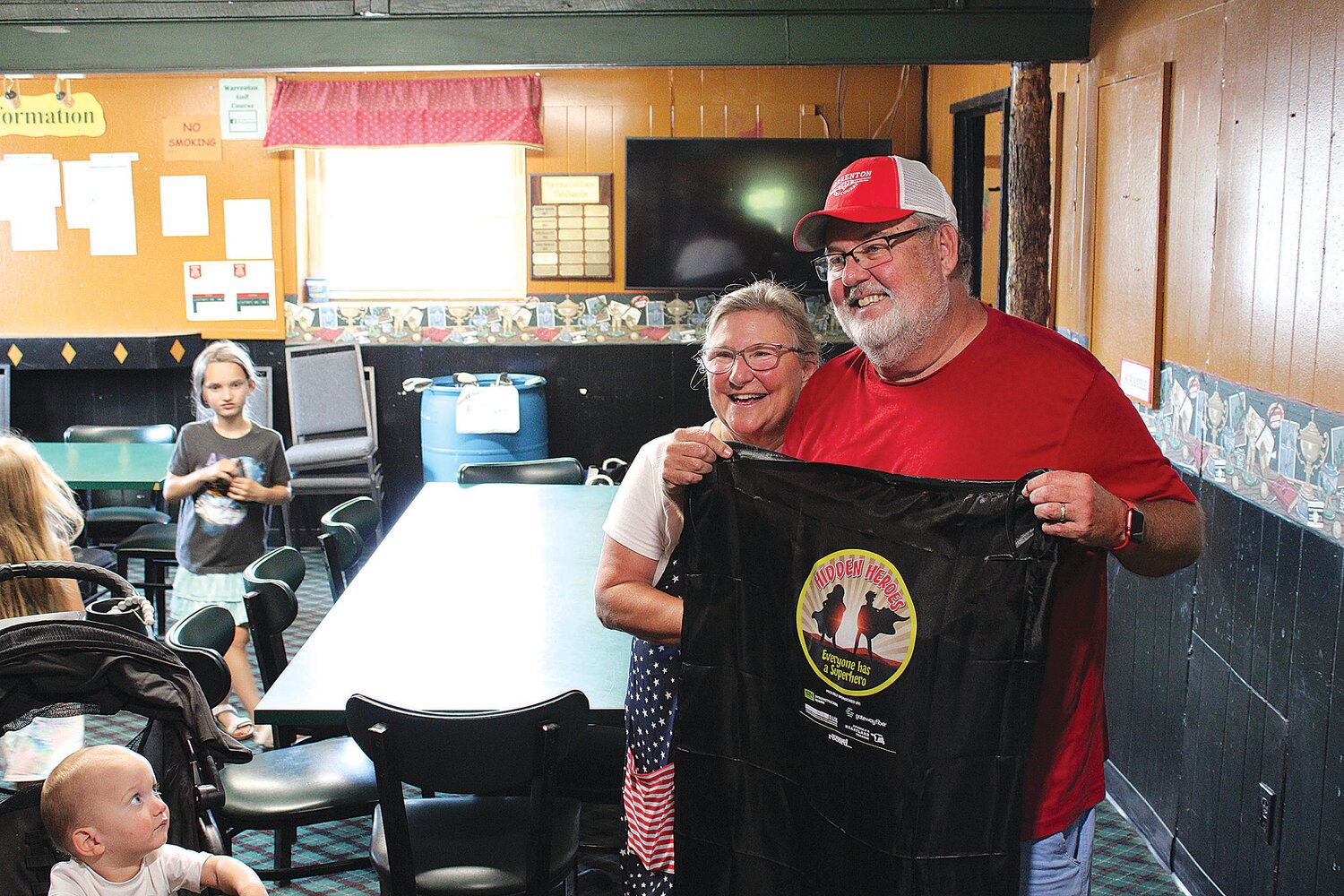 Rich Barton was honored as a Hidden Hero by the Warren County Record. Here he poses with his cape and his wife, Heidi.