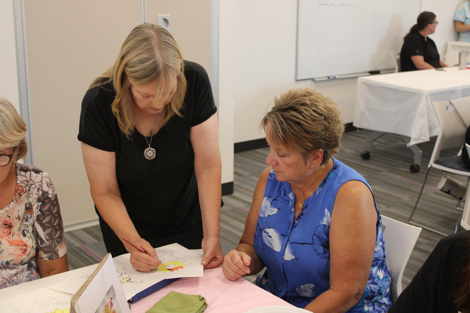 Instructor Carol Peper works with Diane Buxton on her watercolor painting.